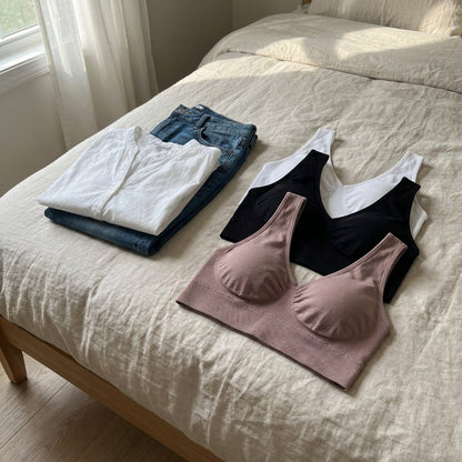 Les trois soutiens-gorge poses sur un lit a cote d'un chemisier blanc et d'un jean
