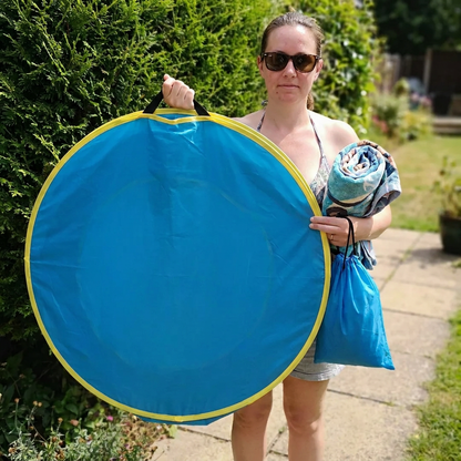 La tente repliée à plat, portée d'une main avec son sac