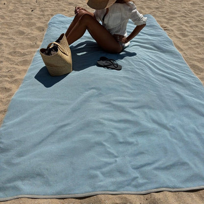 Le drap ZéroSable déplié sur le sable, une personne assise dessus