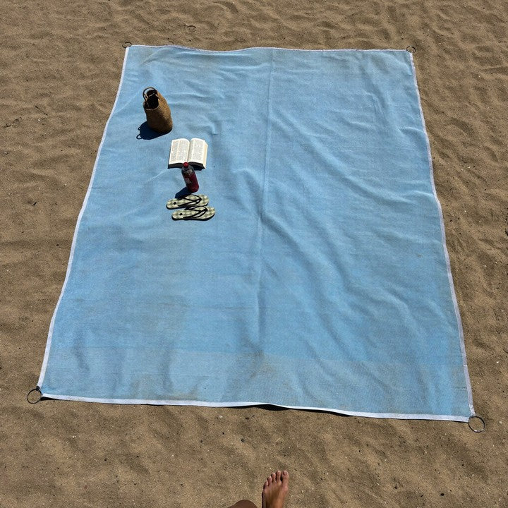 Vue de dessus du drap ZéroSable sur la plage avec sac et livre