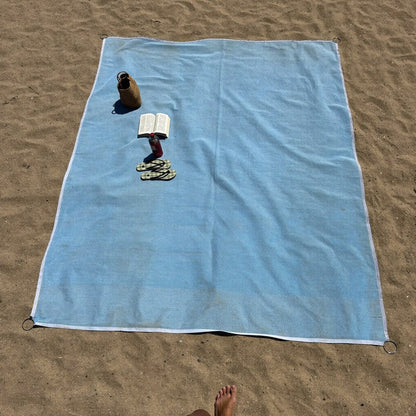 Vue de dessus du drap ZéroSable sur la plage avec sac et livre